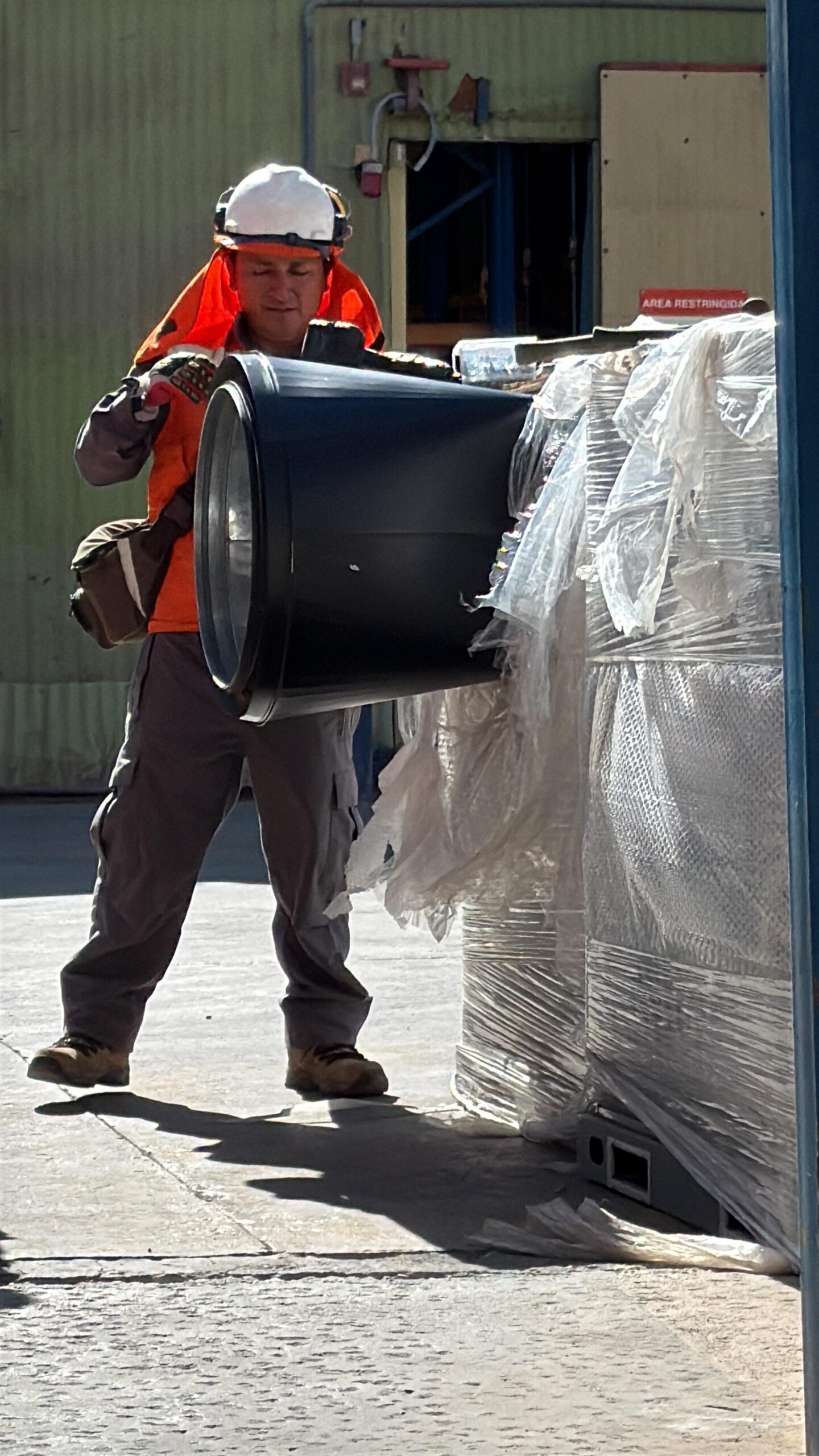 Trabajador transportando ducto de climatización en faena