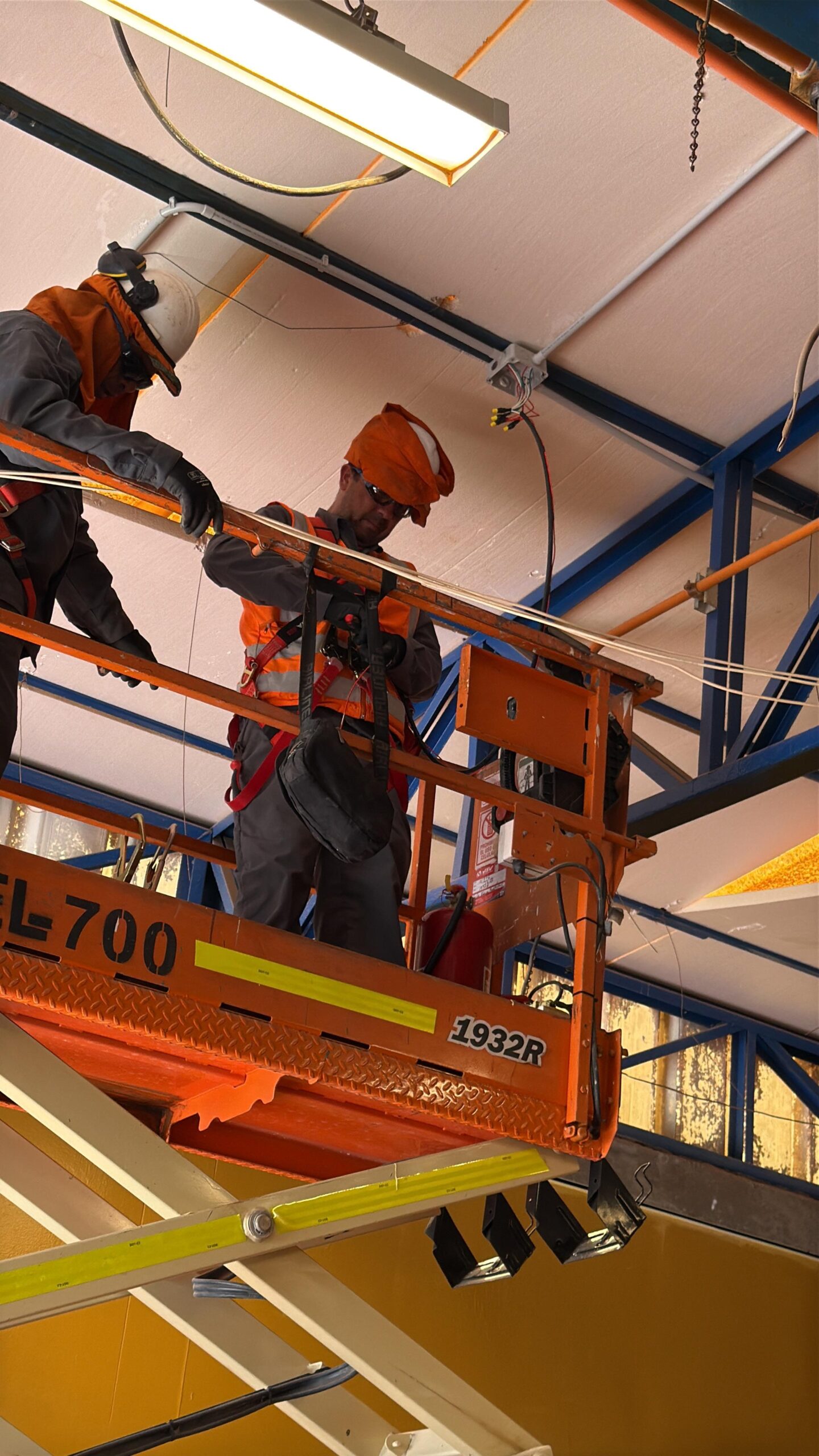 Trabajadores en plataforma elevadora realizando instalación de climatización en altura